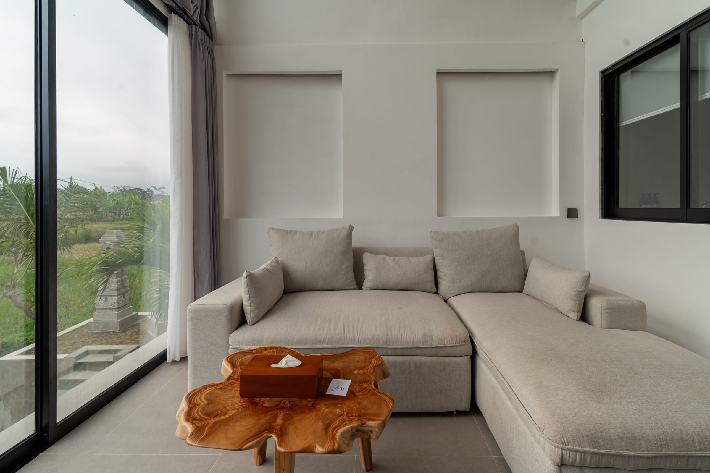 Sofa and TV console facing tall windows onto the garden and a stone shrine